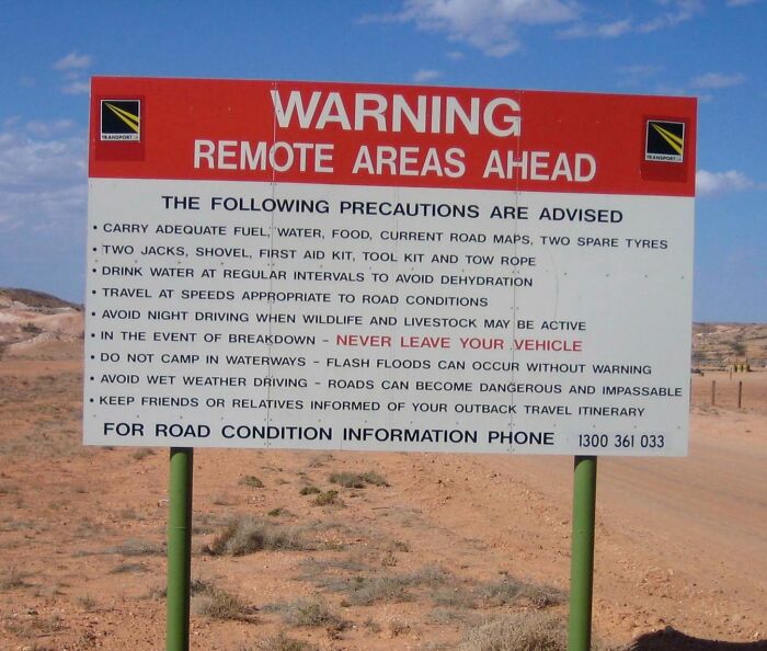 Warning sign in remote area advises precautions for travelers in creepy and unsettling outback conditions.