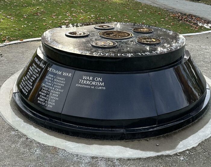 Black memorial monument listing war names including Vietnam War and War on T*******m, capturing a creepy unsettling moment outdoors.