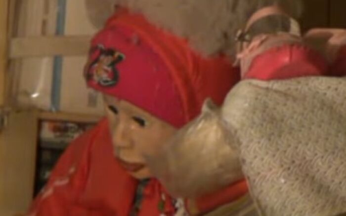 Two creepy and unsettling dolls in red clothing captured in a dimly lit room, creating a chilling moment.