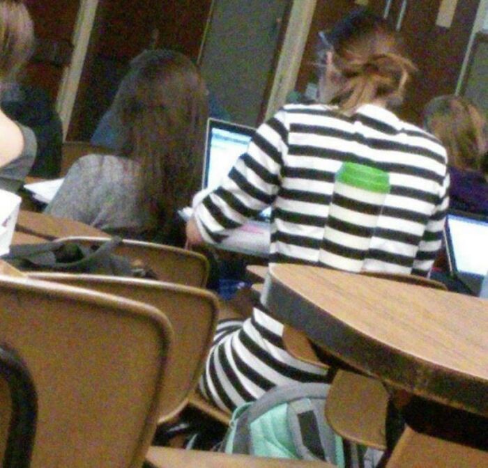 Person wearing a black and white striped outfit that matches the chair, blending perfectly with surroundings in a classroom setting.