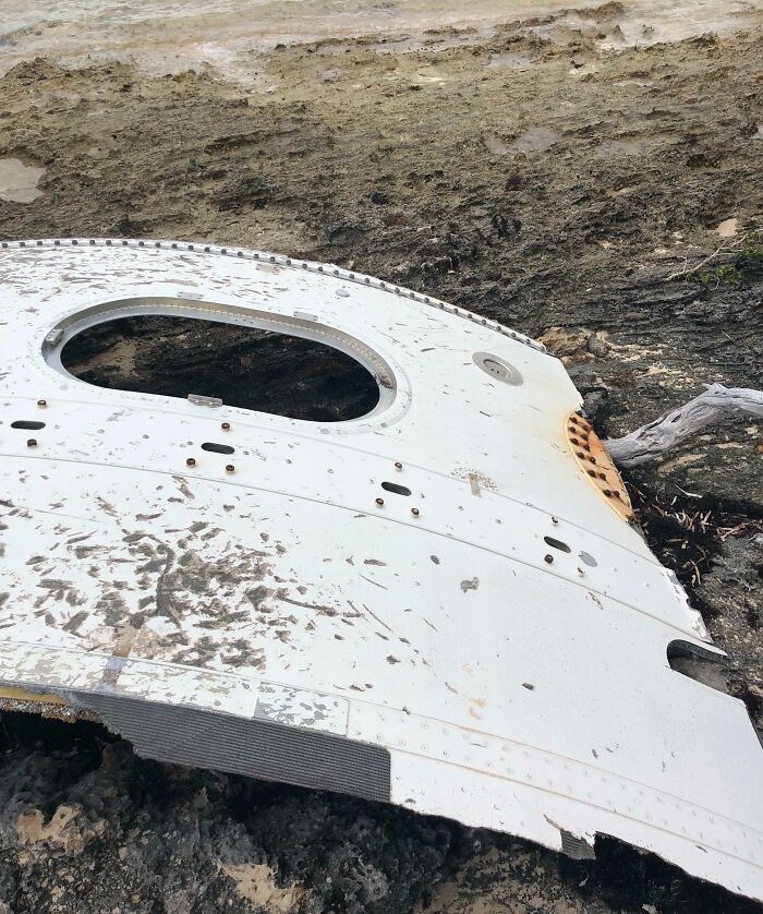 Large airplane debris found at the beach surrounded by sand and rocks as an interesting and bizarre discovery.