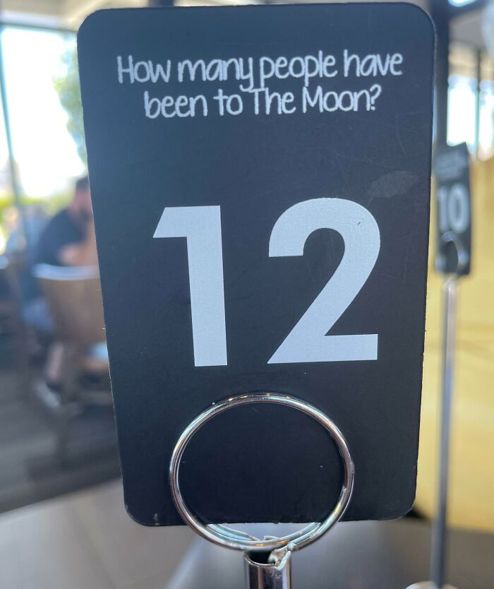 Table number 12 at a creative bar and restaurant featuring a trivia question about how many people have been to the moon.