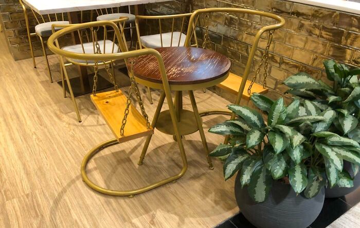 Unique bar seating with swing chairs and wooden table at a creative bar or restaurant setting with modern decor plants.