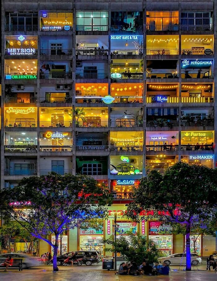 Multi-story building with various brightly lit bars and restaurants showcasing creativity at night.