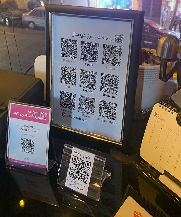 Creative bar digital payment display with multiple cryptocurrency QR codes on a sleek black countertop.