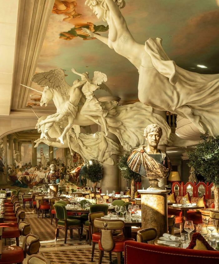 Elegant bar and restaurant interior featuring classical sculptures and artistic ceiling, showcasing creativity in global dining venues.
