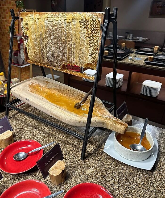 Creative honeycomb display at a bar and restaurant showcasing fresh honey dripping into a wooden tray for guests.