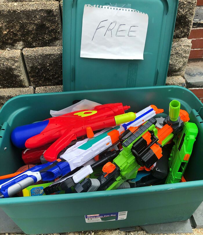 Green bin filled with colorful toy guns and a handwritten free sign, showing wholesome-kind-neighbors sharing.