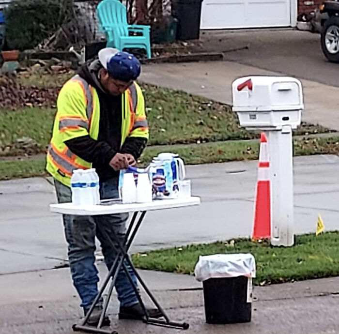 Man in a safety vest setting up water bottles on a table outside, showing wholesome kind neighbors community spirit.