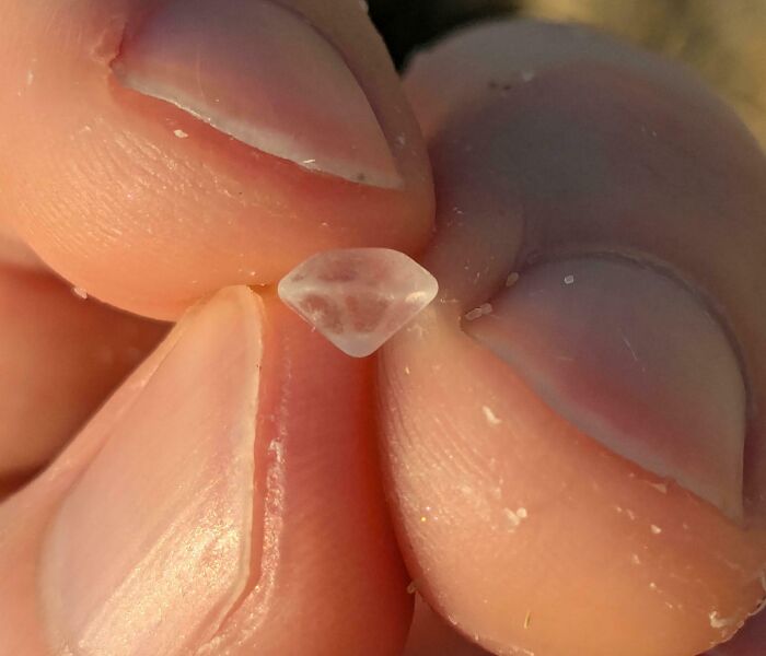 Close-up of a small translucent crystal found at the beach, showcasing one of the interesting and bizarre beach discoveries.