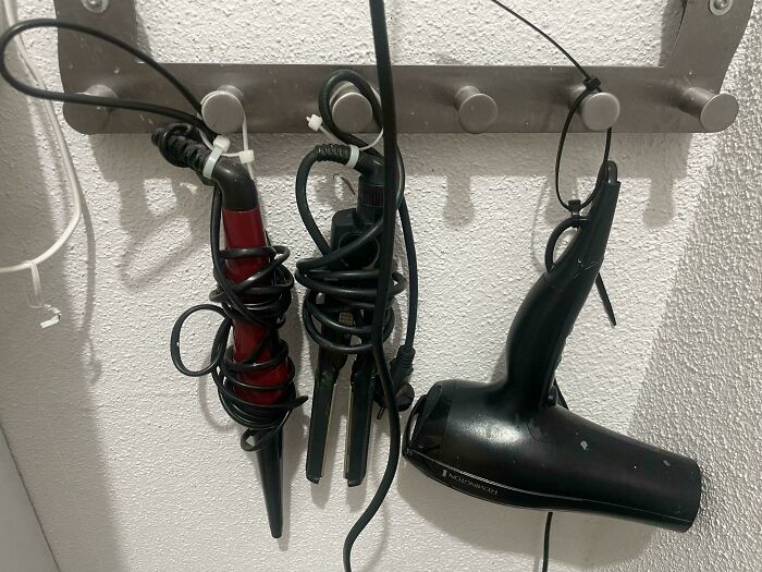 Hair styling tools neatly organized by hanging on hooks as a genius life hack for easy storage and access.