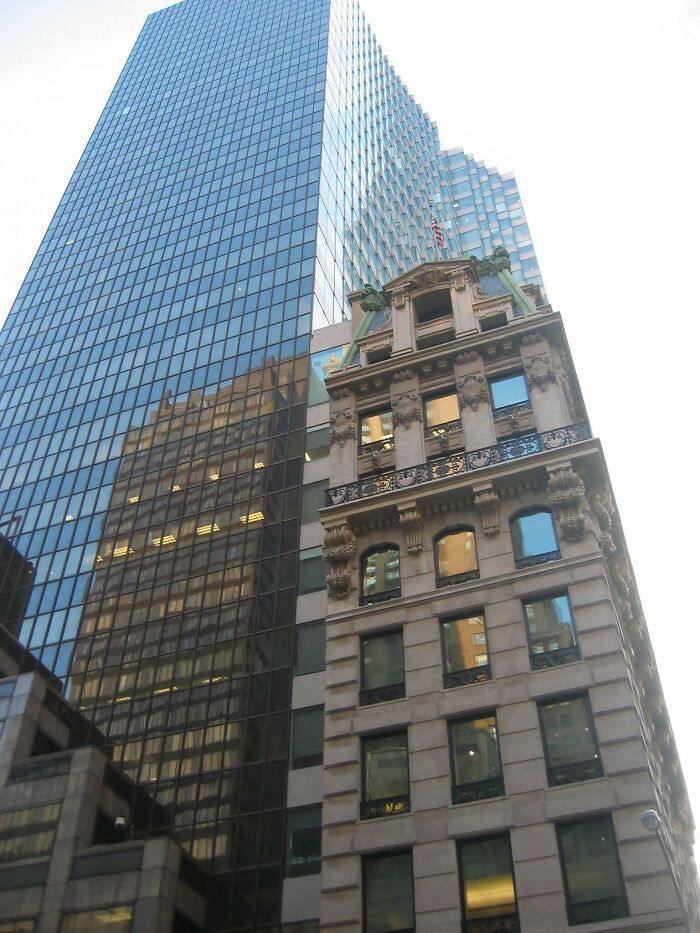 Old versus modern architecture shown by a historic ornate building next to a sleek glass skyscraper in a cityscape.