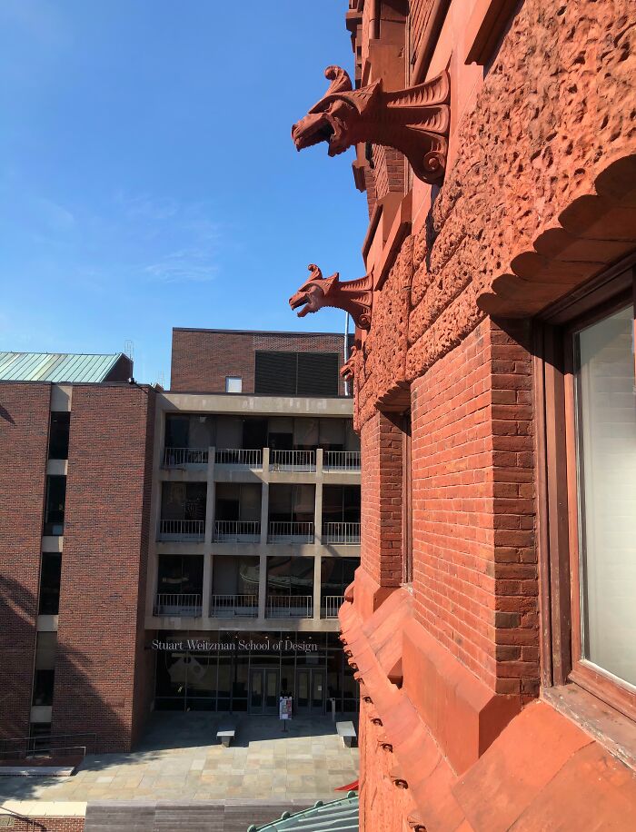 Old versus modern architecture shown with detailed red brickwork and carved gargoyle contrast against simple modern building facade.