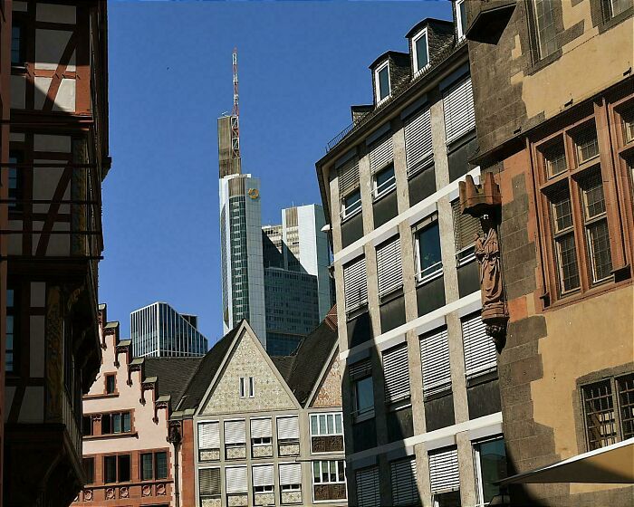 Old versus modern architecture contrast shown with historic European buildings in the foreground and modern skyscrapers in the background.