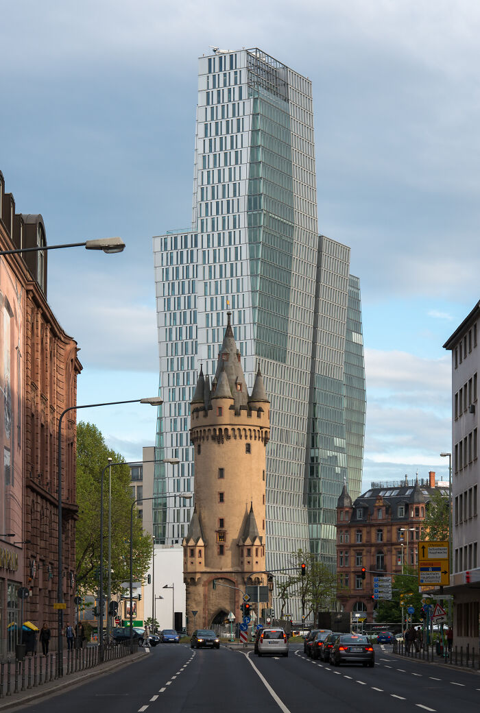 Historic tower contrasting with a modern glass skyscraper in an urban setting showcasing old versus modern architecture.
