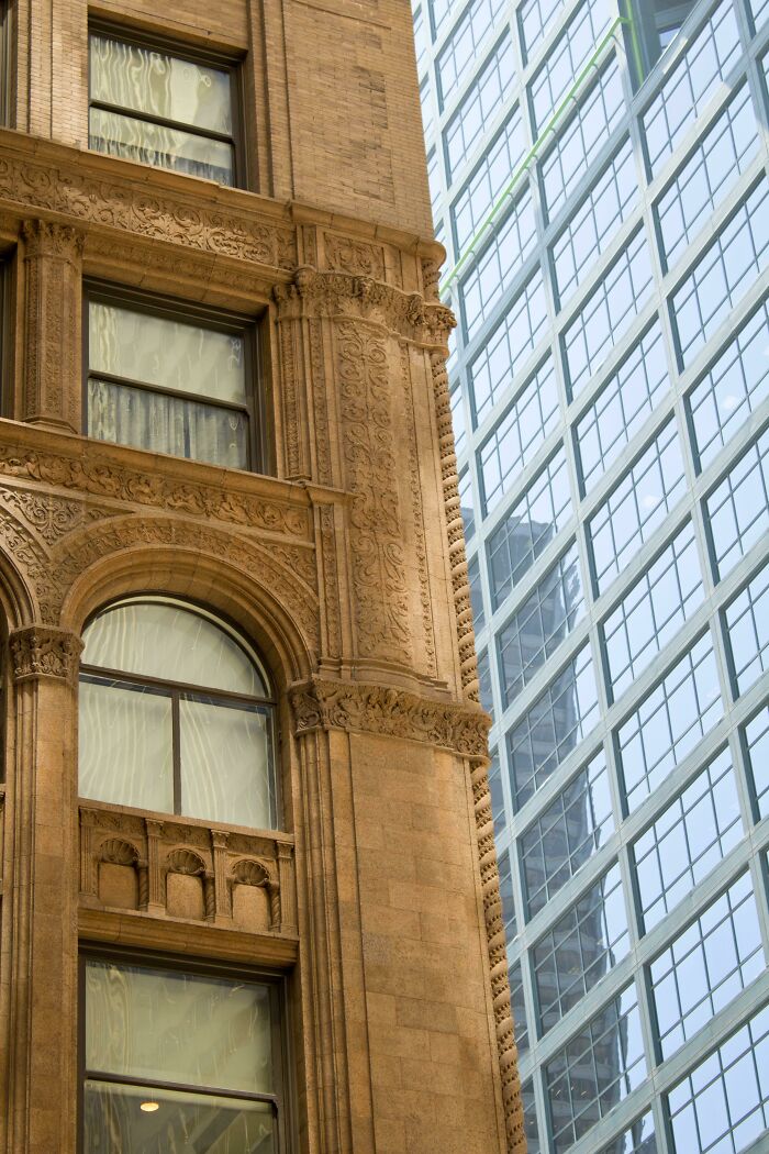 Ornate old architecture next to sleek modern glass building showcasing old versus modern architecture contrast.