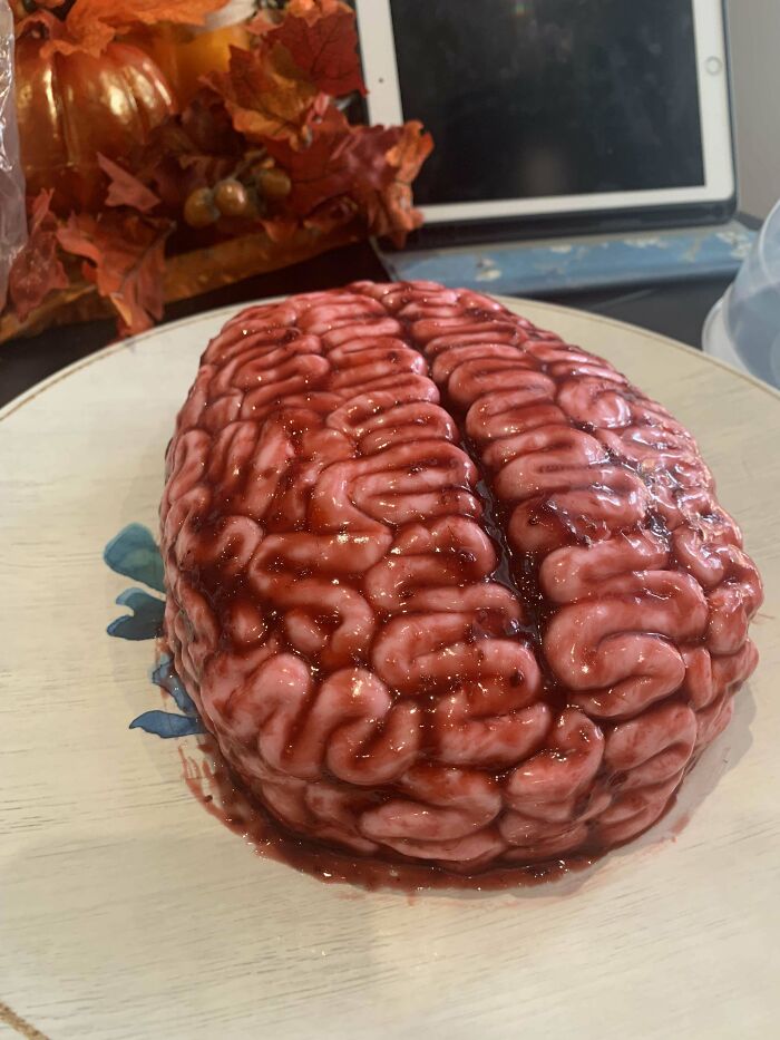 Realistic brain-shaped baked goods with glossy red syrup on a plate, showcasing creative and gorgeous baked goods skills.