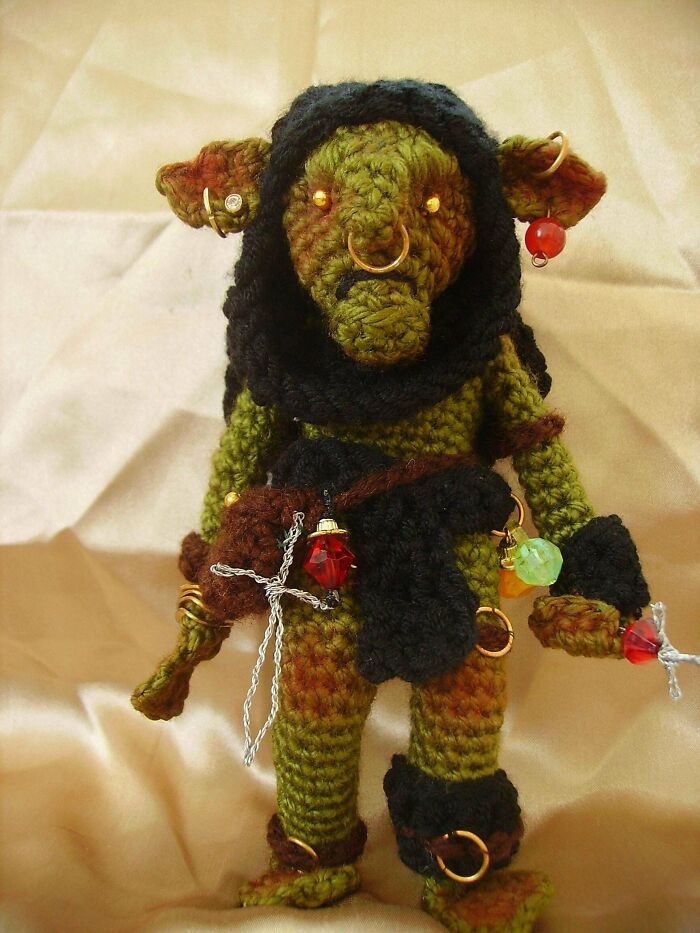 Crocheted fantasy goblin figure adorned with beads and rings, showcasing detailed crocheting skills and creative project design.