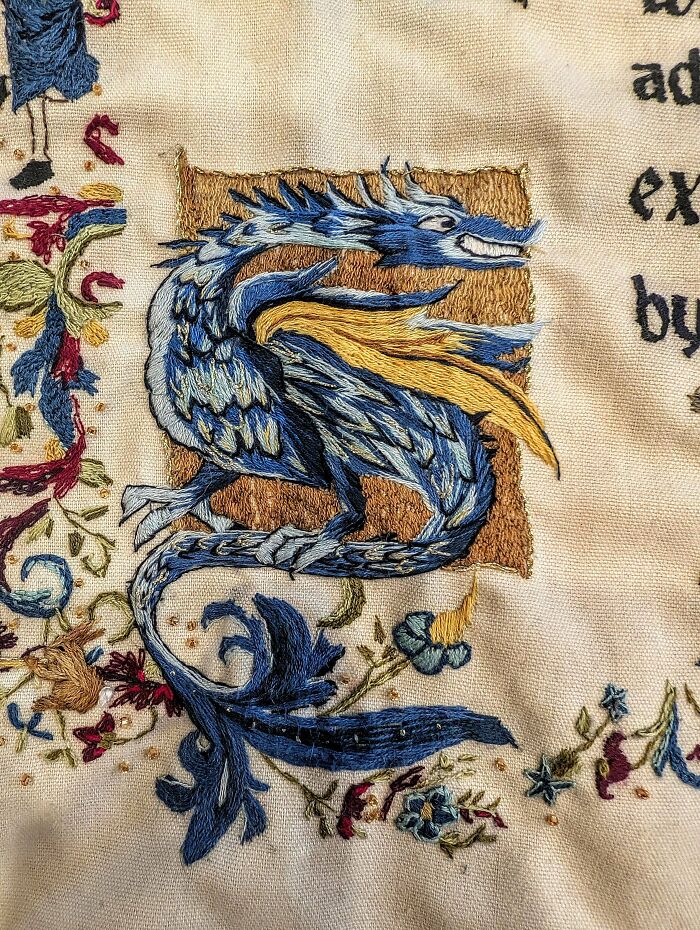 Detailed embroidery creation depicting a blue and gold dragon amidst intricate floral patterns.