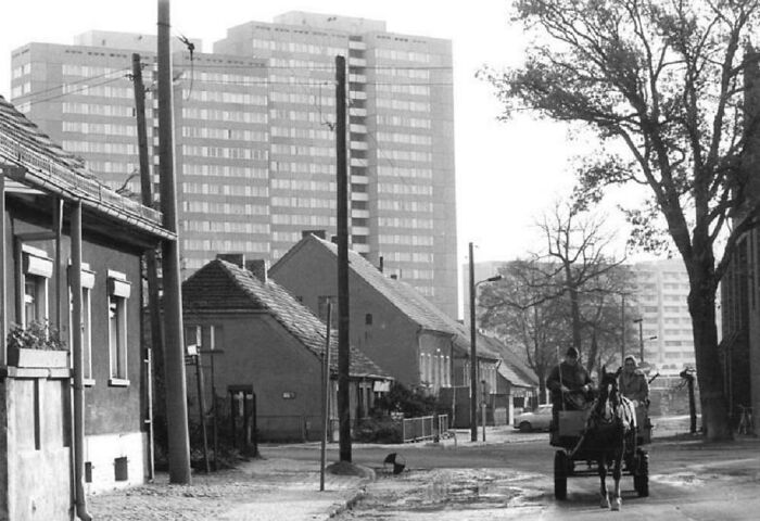 Black and white image showing old versus modern architecture with traditional houses and tall modern buildings in the background.