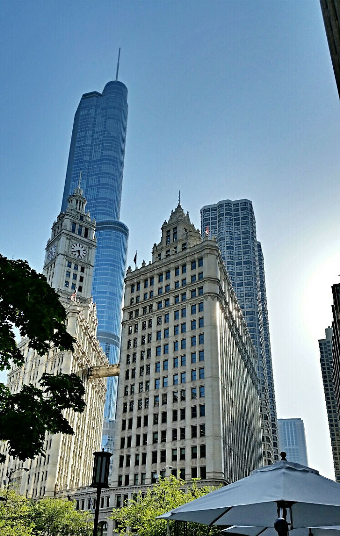 Old versus modern architecture with historic clock tower and sleek glass skyscraper in a city skyline on a clear day.