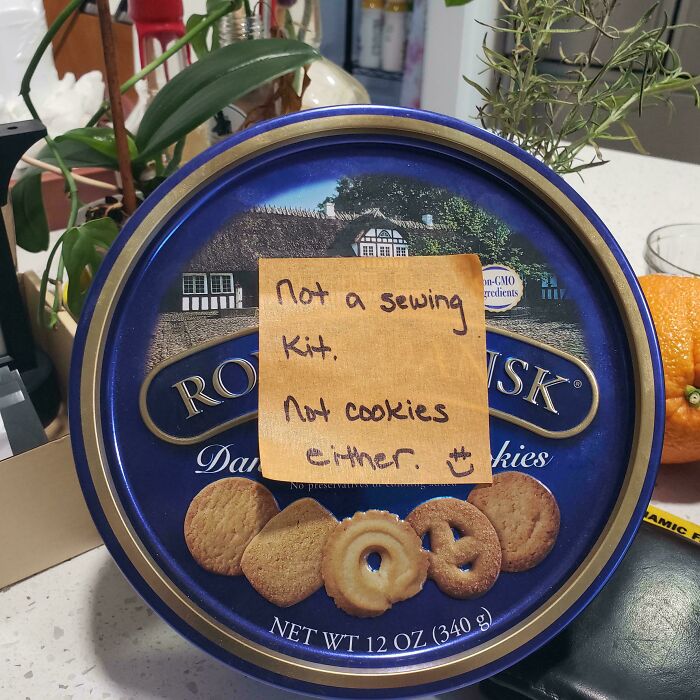 Round cookie tin with a humorous handwritten note reminding not to take life too seriously.