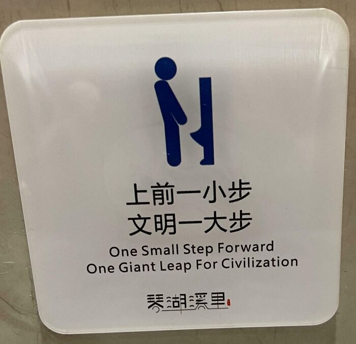 Sign with humorous message in English and Chinese encouraging a small step forward as a giant leap for civilization, random notes humor.