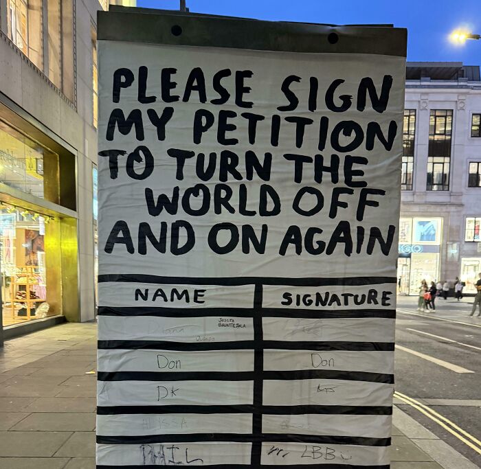 Street sign humorously asking people to sign a petition to turn the world off and on again with names and signatures.