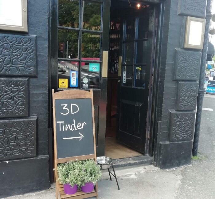 Chalkboard sign outside a black pub door with humorous message 3D Tinder, illustrating random funny notes.
