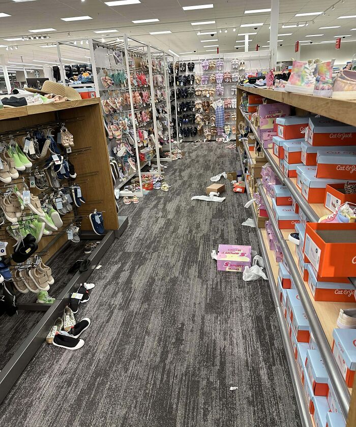 Messy shoe store aisle with scattered boxes, shoes off shelves, and discarded packaging showing selfish people causing disorder.