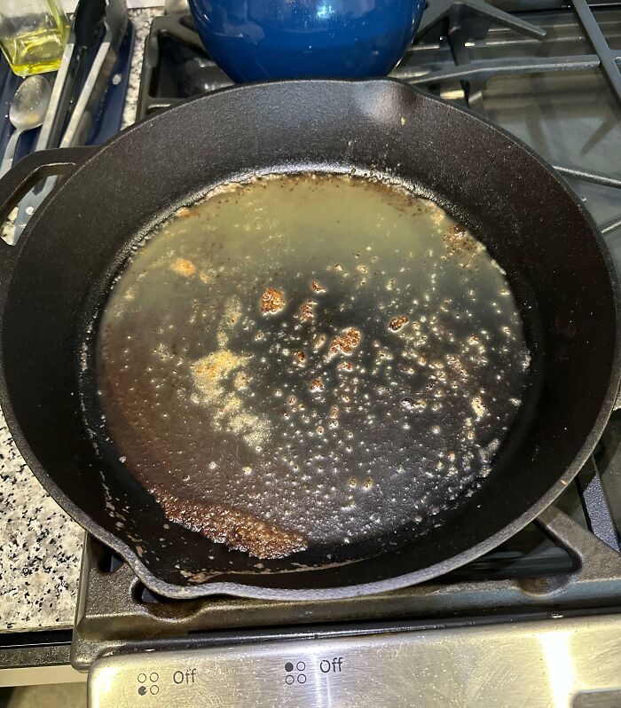 Cast iron pan with burnt food residue and oil, illustrating selfish actions that made life harder for everyone else.