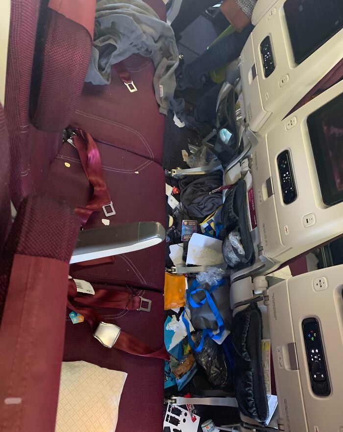 Messy airplane seats with scattered trash and belongings, showing selfish people losing all common decency in public spaces.