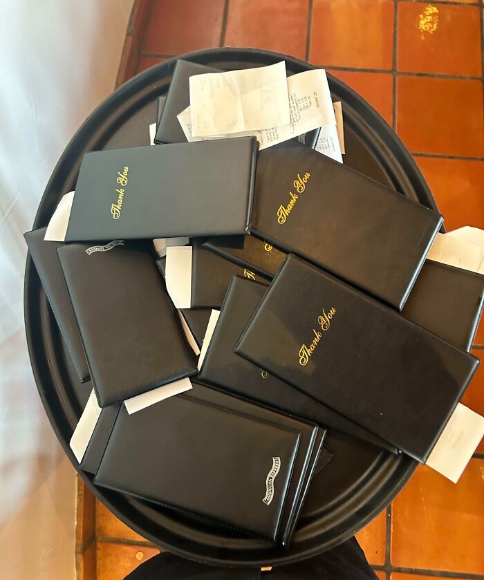 Pile of black receipt holders on a tray, highlighting selfish people causing inconvenience and lost common decency.