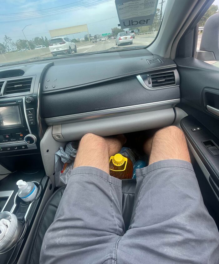 Passenger with legs stretched out in front seat of car, blocking space and making life harder for others in shared ride.