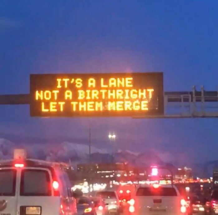 Highway digital sign humorously reminding drivers to let others merge, reflecting random notes and messages about life.