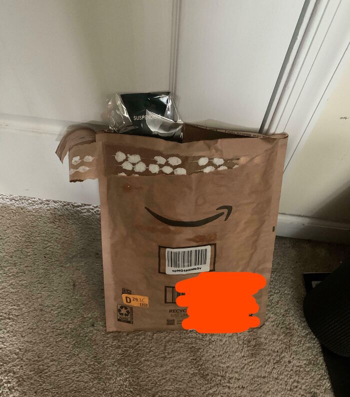Worn Amazon package left on the floor, showing selfish people lost decency and making life harder for others.