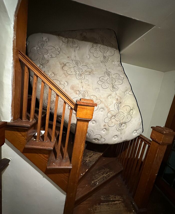Mattress stuck on narrow wooden staircase illustrating selfish people losing all common decency and making life harder for everyone else.
