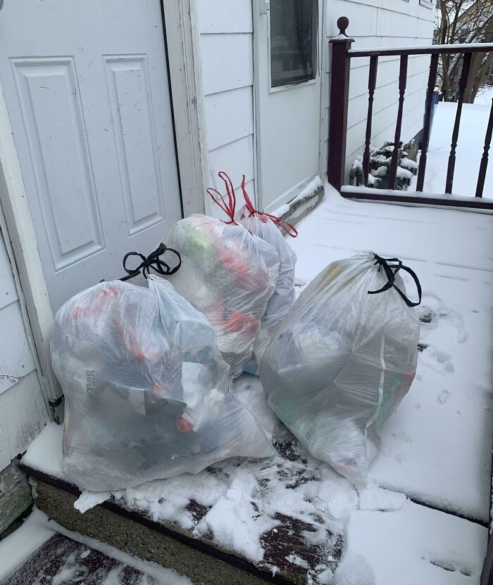 Three large tied trash bags left on a snowy porch illustrating selfish people causing problems for others.