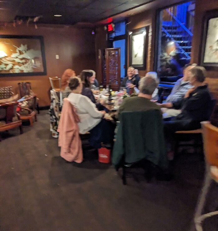Group of people sitting closely around a table indoors, illustrating selfish people making life harder for everyone else.