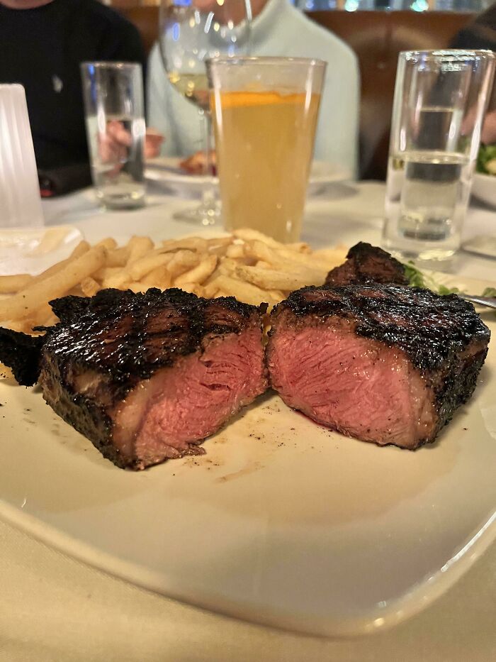 Grilled steak cooked medium rare with crispy fries served on a white plate in a restaurant setting