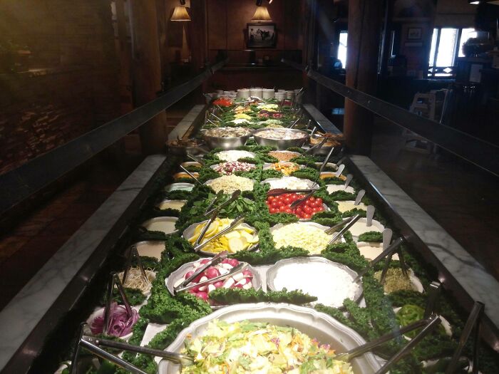 Salad bar display with various fresh vegetables and toppings in a restaurant setting, capturing restaurant workers' challenges.