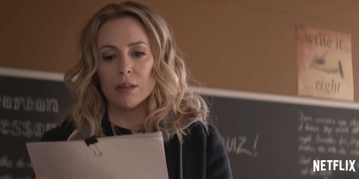 Woman reading papers in a classroom setting, shown in a scene from Netflix movies that turned out to be letdowns.