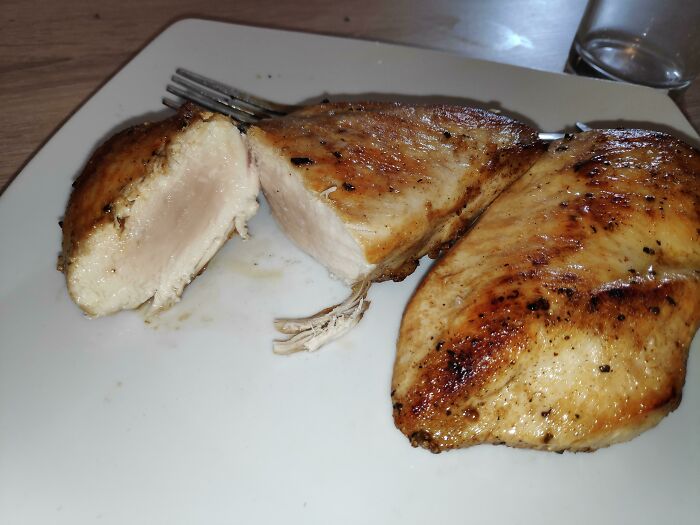 Two pieces of undercooked grilled chicken breast on a white plate, a moment restaurant workers feared to serve.
