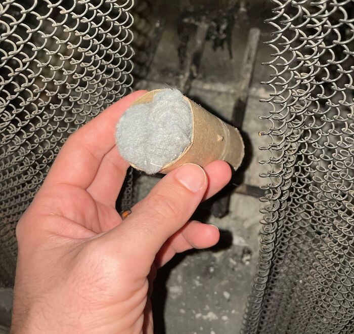 Hand holding a cardboard tube stuffed with steel wool, demonstrating a genius life hack for fire starting.