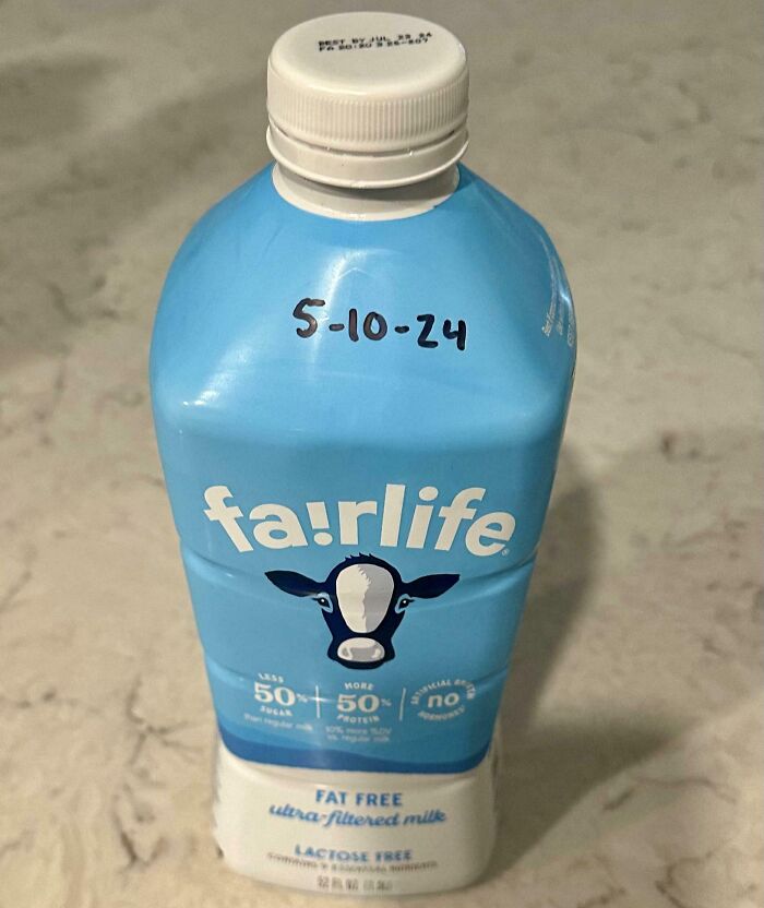 Blue fairlife milk carton with handwritten expiration date on a beige marble surface, illustrating genius life hacks in everyday use.