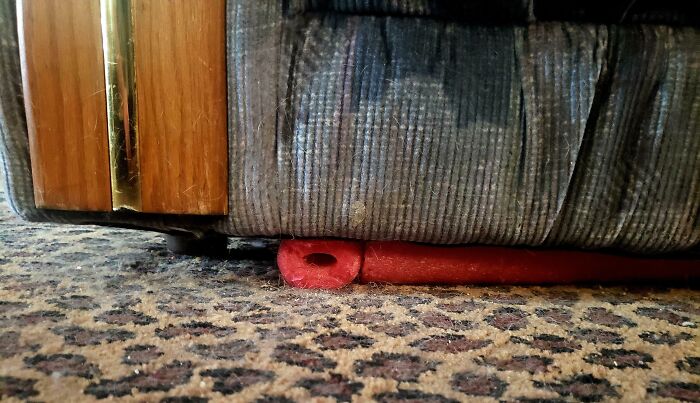 A genius life hack showing how to use a foam pool noodle to support and level a couch on a carpeted floor.