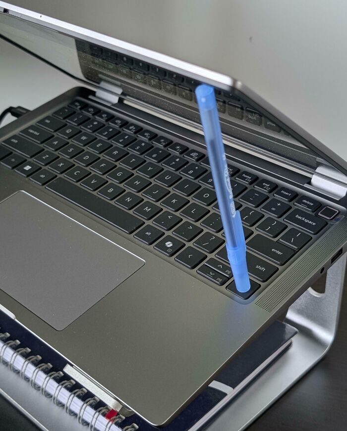 Laptop keyboard with a blue pen inserted into a keyhole, demonstrating one of the most genius life hacks people actually use.