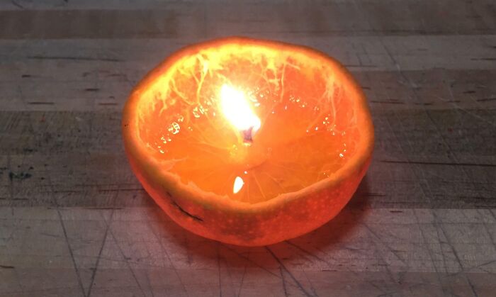 Orange fruit candle made with a halved orange and lit wick, demonstrating a genius life hack in use.