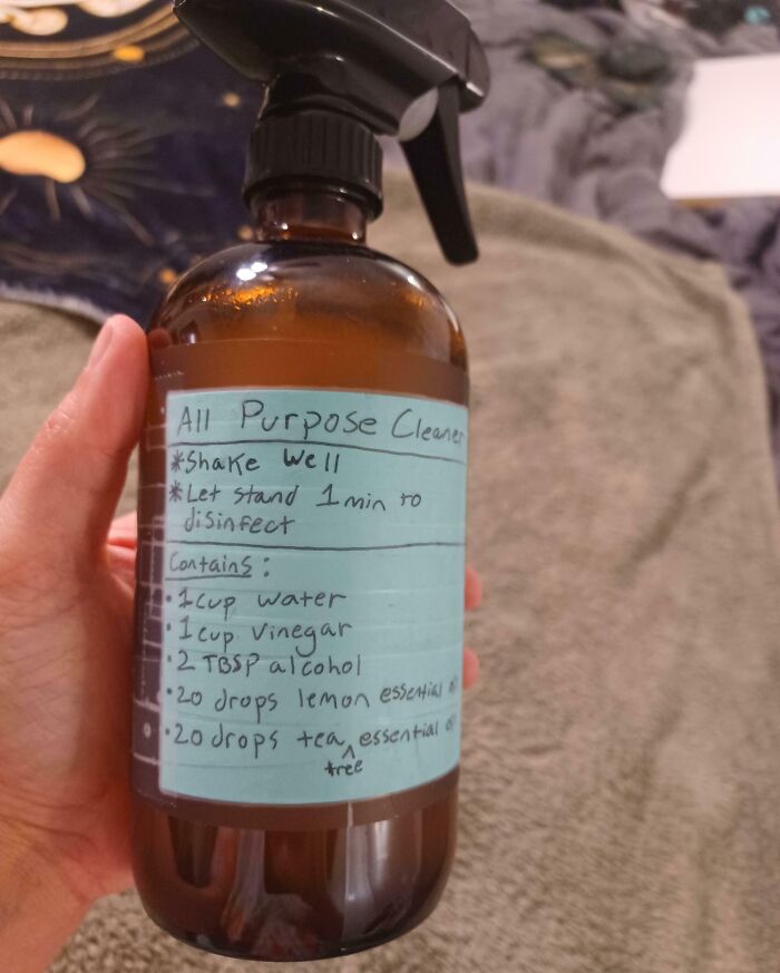 Hand holding a homemade all-purpose cleaner bottle with recipe label showing genius life hacks people actually use.