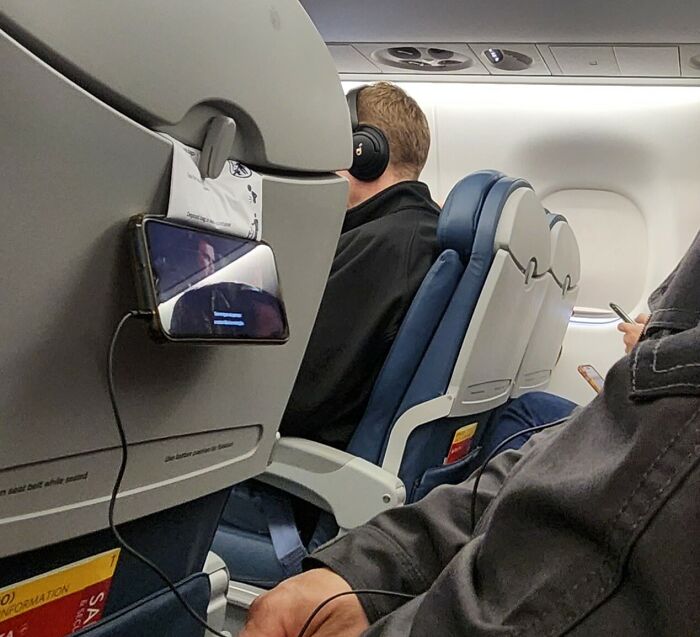 Phone holder hack on airplane seatback using a hook to watch media hands-free, a genius life hack in everyday travel.